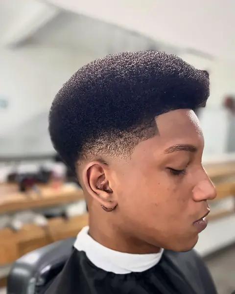 Jovem com cabelo afro modelado em formato alto e degradê nas laterais
