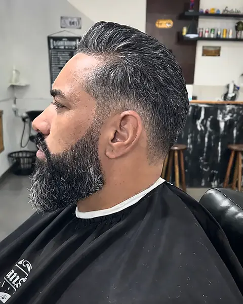 Cliente de perfil com barba cheia alinhada e cabelo penteado para trás
