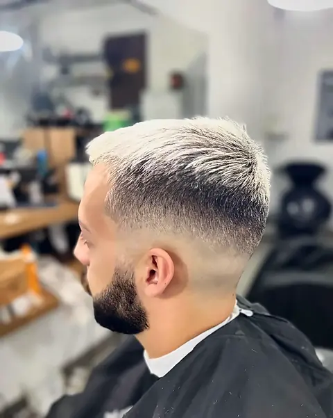 Cliente com cabelo platinado, degradê e barba alinhada