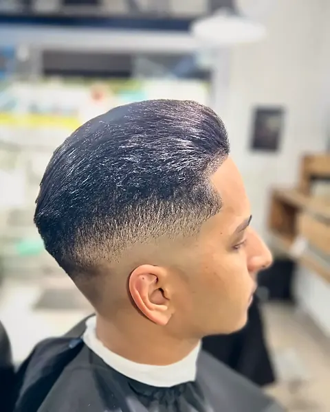 Cliente de perfil com topete penteado e degradê baixo, feito na San Andreas