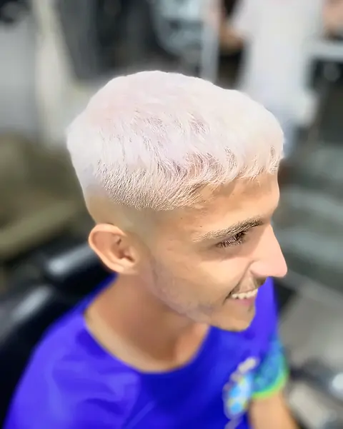 Cliente sorrindo com cabelo platinado e degradê baixo